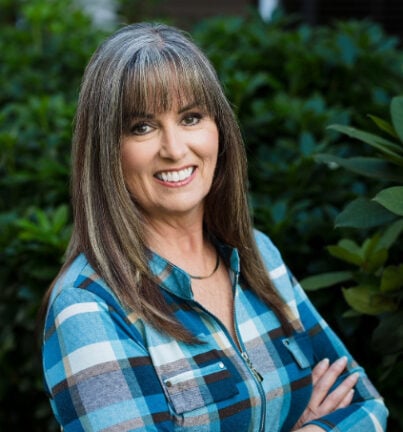 a smiling woman with long hair and a plaid shirt